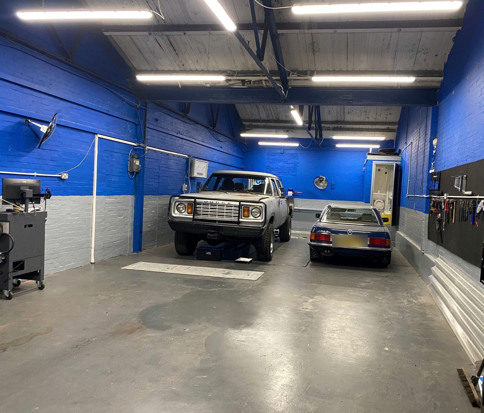 Inside Willesden MOT: two cars in the bright blue workshop